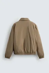 Cazadora regular fit de tejido técnico y mezcla de algodón con ligero acolchado interior, color marrón. Presenta cuello solapa, manga larga, bolsillos de vivo en la cadera, bolsillo interior, y acabados elásticos en puños y dobladillo. Cuenta con cierre frontal de cremallera.