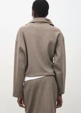 Jersey color tostado con cuello solapa y cierre de cremallera corta en el pecho, de manga larga y diseño holgado.