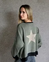 Buzo de punto con diseño de rayas verticales en tonos tostado y beige, con una estrella grande en la espalda y terminaciones en color verde oliva. Presenta un corte holgado y mangas anchas.