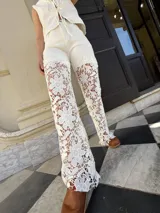 Pantalón de gabardina color crudo con encaje floral blanco en la parte inferior de las piernas.