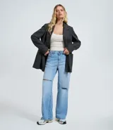 Pantalón de jean modelo wide leg en color azul medio, con cintura baja y corte holgado. Presenta roturas decorativas en las rodillas, bolsillos funcionales, cierre frontal con botón y cremallera, y trabillas para cinturón.