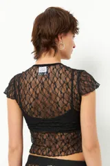 Top de encaje negro con escote en V y tiras de terciopelo. Es de manga corta y corte ajustado.