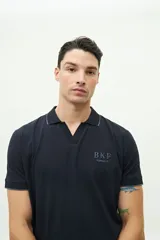 Polo marrón de manga corta con cuello en V y ribete blanco en cuello y mangas.