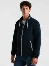 Campera rompevientos azul marino con cierre frontal, cuello alto con doble raya blanca, capucha oculta, puños elásticos y bolsillos con cierre.