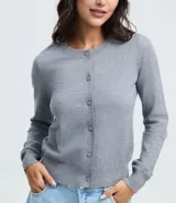 Cardigan de punto color gris, con cuello redondo, manga larga y cierre frontal con botones. Presenta puños y bajo acanalados, con un diseño clásico y versátil.