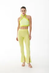 Pantalón tipo calza de tiro alto, color amarillo lima, con textura acanalada y aberturas frontales en el ruedo.