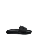 Ojota tipo slide marca Umbro, color negro, con diseño ergonómico y logo de la marca en relieve sobre la banda superior.