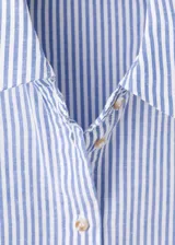 Camisa crop de manga corta con diseño de rayas celestes y blancas, cuello camisero, cierre frontal de botones y un bolsillo parche delantero.