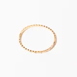 Pulsera rígida dorada con diseño geométrico y pequeños cristales engarzados.