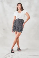 Minifalda negra con bordado blanco de motivos geométricos y terminación festoneada.