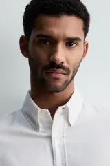 Camisa de corte regular fit confeccionada en tejido de algodón con efecto lavado. Presenta cuello abotonado, manga larga con puños abotonados, bolsillo en el pecho y cierre frontal con botones.