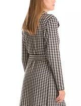 Chaqueta larga de tejido de punto con estampado de pata de gallo en blanco y negro. Presenta cuello de solapa, cierre frontal con lazo ajustable en la cintura y bolsillos aplicados en el frente.