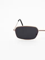 Lentes de sol con marco metálico color dorado y forma rectangular. Poseen cristales con degradado en tonos marrones y patillas finas con terminales negros.