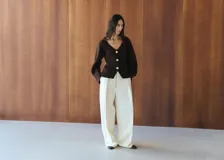 Chaqueta de punto color marrón oscuro, con escote en V, mangas largas abullonadas y cierre frontal con grandes botones dorados grabados.