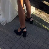 Sandalia de gamuza color marrón, con taco ancho, punta fina y tira ajustable al tobillo. Incluye detalle metálico en la puntera.
