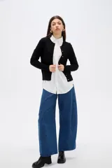 Saco de punto al cuerpo, color negro, con cuello redondo, manga larga y cierre frontal con botones pequeños.
