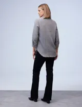 Camisa celeste de tencel con cuello con solapa, escote en V y abertura central con botones. Tiene bolsillos delanteros, mangas largas regulables con presilla y ruedo desflecado.