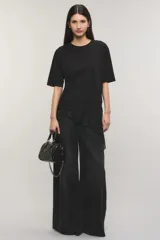 Remera negra de corte oversize, con escote redondo, mangas cortas y detalle de tajo irregular con terminación en puntilla en el ruedo. Confeccionada en jersey de algodón.