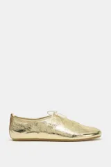 Zapato tipo bailarina de piel con acabado metalizado dorado, detalle de lazo frontal y tirador en el talón.