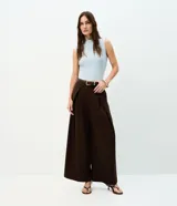 Pantalón de sastrería en crepé color marrón, de modelaje barrel y tiro alto con cintura estructurada. Presenta pinzas frontales profundas, bolsillos embutidos y caída amplia de corte recto.