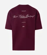 Remera de corte oversized color bordó, con cuello redondo y manga corta. Presenta un estampado en la espalda con lettering manuscrito que incluye las ciudades Paris, Tokyo y New York, junto con detalles tipográficos adicionales.