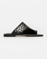 Sandalias planas blancas de cuero, con tira ancha sobre el empeine adornada con tachas plateadas.
