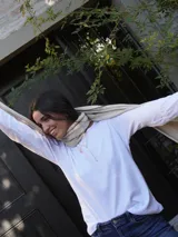 Remera de manga larga en color blanco, con cuello redondo y corte clásico. Presenta un diseño minimalista con un pequeño logo bordado en el pecho.