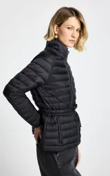 Campera puffer negra de diseño capitoneado, con cuello alto, cierre frontal y ajuste en la cintura mediante cordón. Presenta bolsillos laterales y mangas largas.