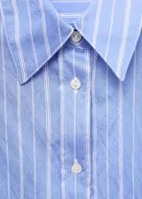 Camisa de corte recto y diseño a rayas verticales, con cuello camisero, cierre frontal de botones y mangas largas con puños abotonados.