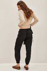 Pantalon cargo de corte recto y acabado satinado, color negro, con bolsillos laterales tipo cargo y puños elásticos en los tobillos.