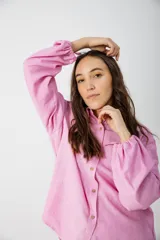 Camisa blanca con estampado de hojas en tonos beige y verde, cuello camisero, mangas largas con lazos en los puños y botones de madera.