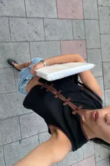 Top negro sin mangas de estilo chino, con ribetes marrones y cierre delantero de nudos tradicionale.