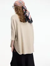 Sweater beige de mangas 3/4, con fit amplio y largo más pronunciado en la parte trasera.