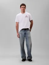Remera blanca de manga corta y cuello redondo de la marca Calvin Klein, con calce regular. Presenta un diseño gráfico frontal en forma de pirámide formado por las letras CK en color bordó.