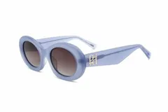 Lentes de sol de mujer, armazón grueso de acetato color celeste translúcido, forma ovalada/redonda. Cristales color café degradado. Detalle metálico dorado con logo en la patilla.