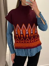 Chaleco de punto morado con cuello alto y diseño geométrico amarillo y azul.