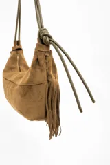 Cartera de hombro con diseño de flecos largos en la parte frontal, confeccionada en material sintético con textura de gamuza. Cuenta con una correa larga ajustable y cierre superior.