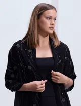 Pashmina o chal negro de gasa, con apliques de brillos plateados en forma de estrellas y líneas curvas.
