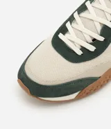 Championes de estilo jogging con diseño de paneles en tonos beige y verde oscuro. Presentan una combinación de malla técnica y refuerzos en material sintético, con suela dentada en color marrón y entresuela blanca.