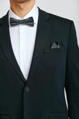 Ambo formal compuesto por saco de corte clásico con cierre de un botón y pantalón de vestir a juego, en color verde oscuro.