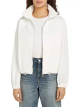 Cortavientos blanco de corte regular, con cuello alto, cierre de cremallera, dos bolsillos con botones, detalles distintivos de Tommy Hilfiger y logo gráfico bordado en el pecho.