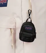 Mini mochila decorativa JanSport color negro, con bolsillo frontal y parche de la marca. Diseñada como accesorio tipo charm para colgar en bolsos o mochilas.