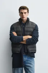 Chaleco acolchado de hombre color negro, con diseño puffer, cuello alto y cierre frontal con cremallera.