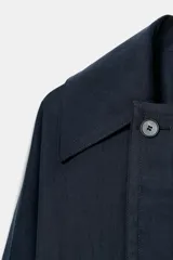 Trench corto de Zara, confeccionado en mezcla de lyocell, color verde militar. Presenta cuello solapa, manga larga con hombro caído y puños con trabilla. Incluye bolsillos delanteros de plastrón, cierre frontal cruzado con botón y cinturón de lazada en el mismo tejido.