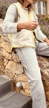 Chaleco color crema con ribete amarillo, de corte recto y sin mangas.