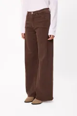 Jean de corte wide leg en color marrón chocolate, con tiro medio y cierre frontal con botón y cremallera. Presenta un diseño de cinco bolsillos y costuras visibles.