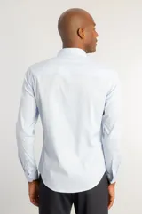 Camisa de manga larga en color celeste, confeccionada en tejido de tricolina con elastano. Presenta un diseño liso, cuello clásico y cierre frontal con botones.