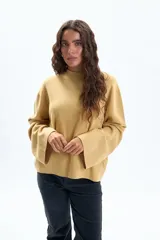 Buzo de tejido de punto color mostaza, de corte holgado, con cuello redondo acanalado y mangas anchas tipo campana.