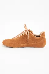 Zapatilla de perfil bajo confeccionada en gamuza color camel, con cordones jaspeados en tonos tierra y suela de goma dentada.
