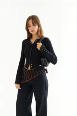 Top de manga larga color amarillo, confeccionado en tejido acanalado con cierre frontal de botones a presión metálicos. Presenta detalles de botones en los puños y un corte ajustado al cuerpo.